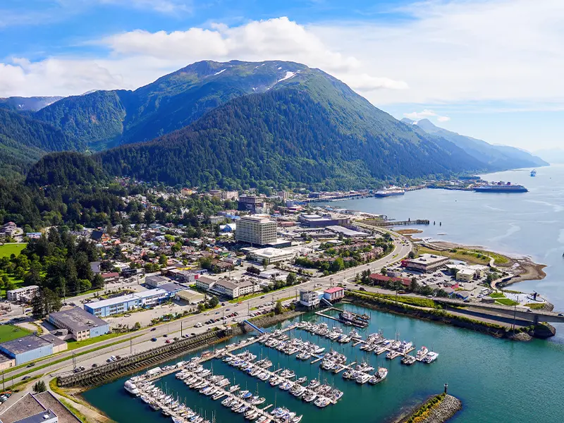 Aerial view of downtown Juneau, Alaska, with the waterfront, harbor, and surrounding mountains